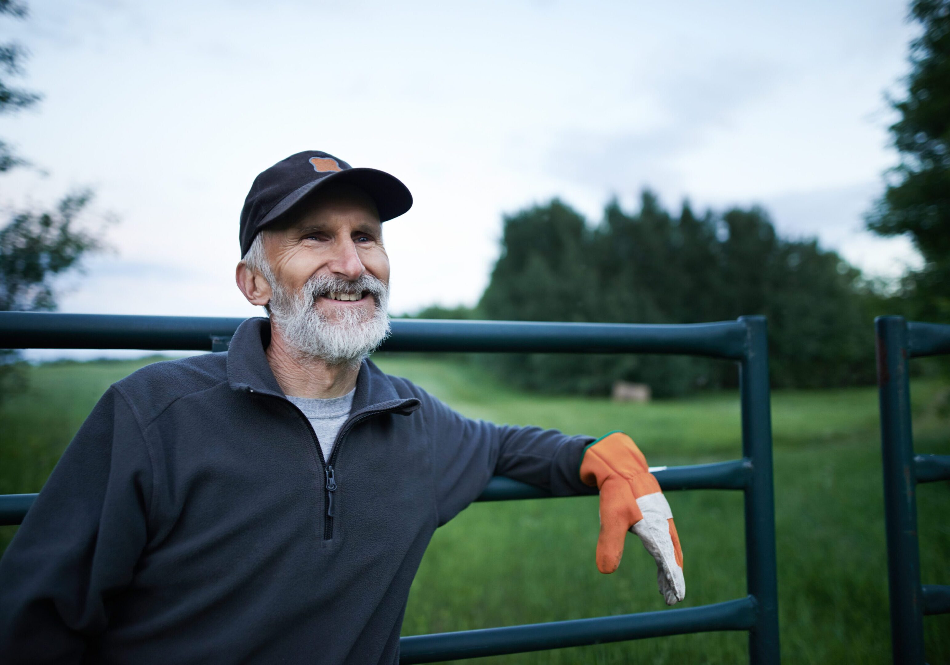 Shot of a mature man standing at the fence of a farm