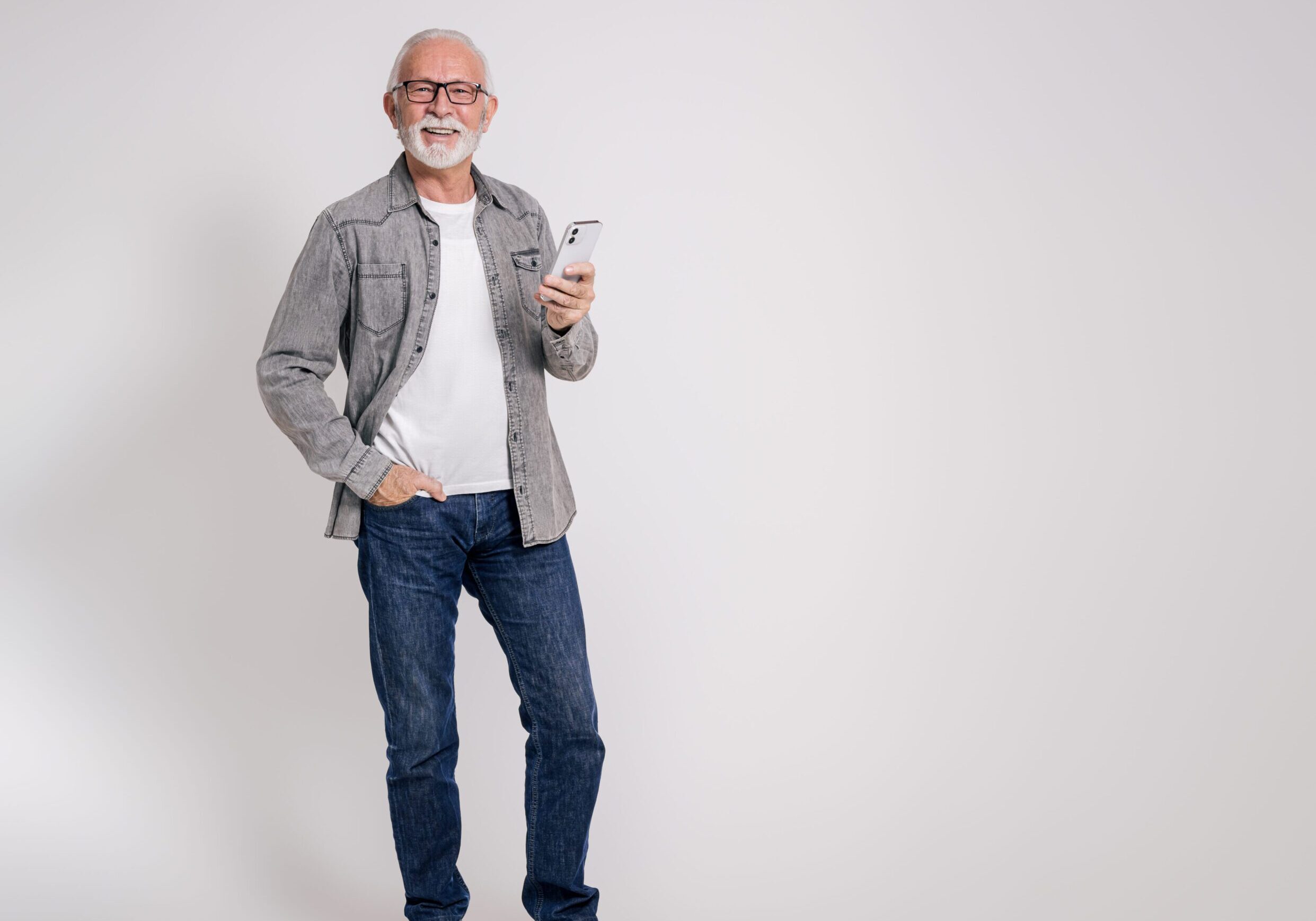 Portrait of confident old male professional with smart phone smiling at camera on white background